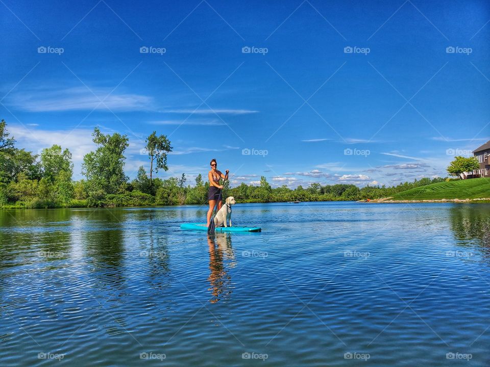 goldendoodle dog and beautiful woman on paddleboard in Lake