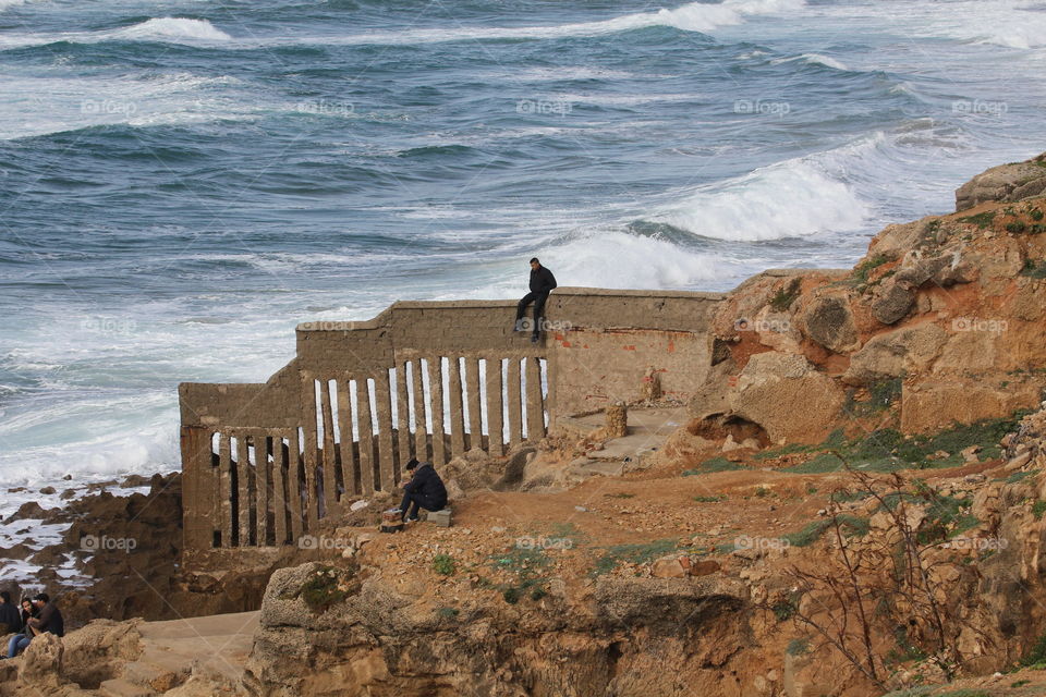Man on a wall watching the waves come in 