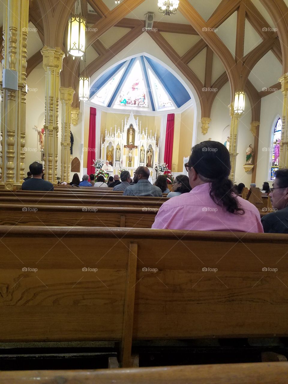 Sitting in the pews of a catholic church during mass.  Listening during the Sunday sermon.