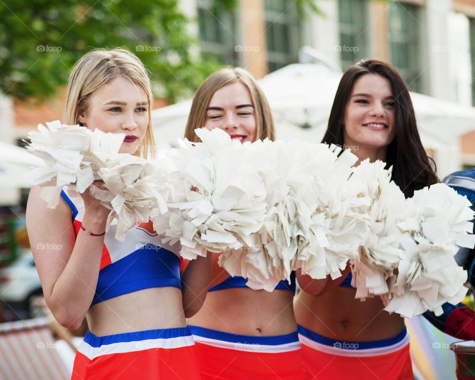 Three smiling cheerleaders holding pom pom