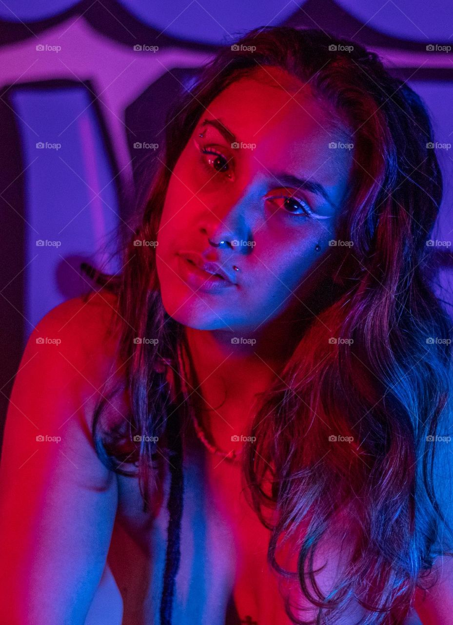 Retrato de garota bonita iluminada sobre luzes azuis e vermelhas.