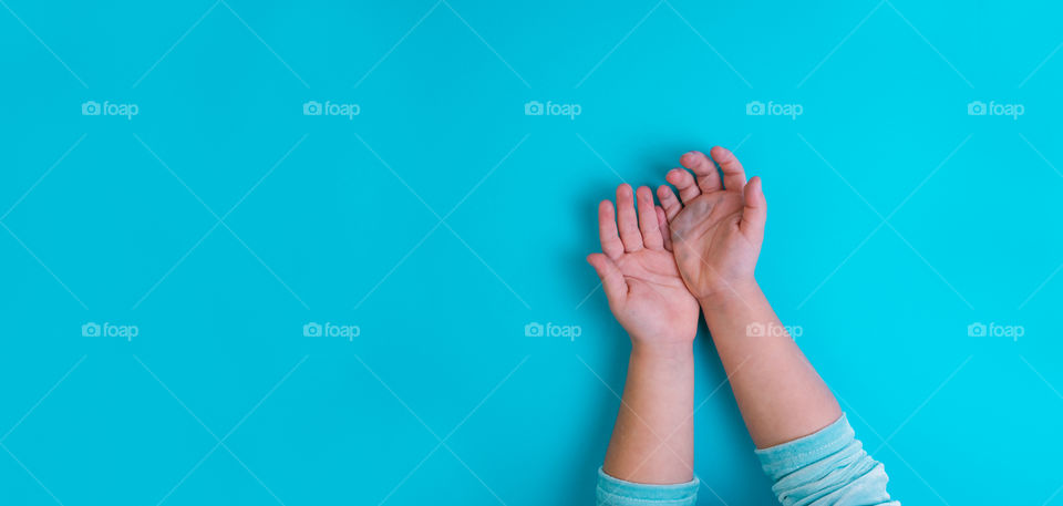 Hands of little girl on blue background. Conceptual. Top view. Copy space. Banner