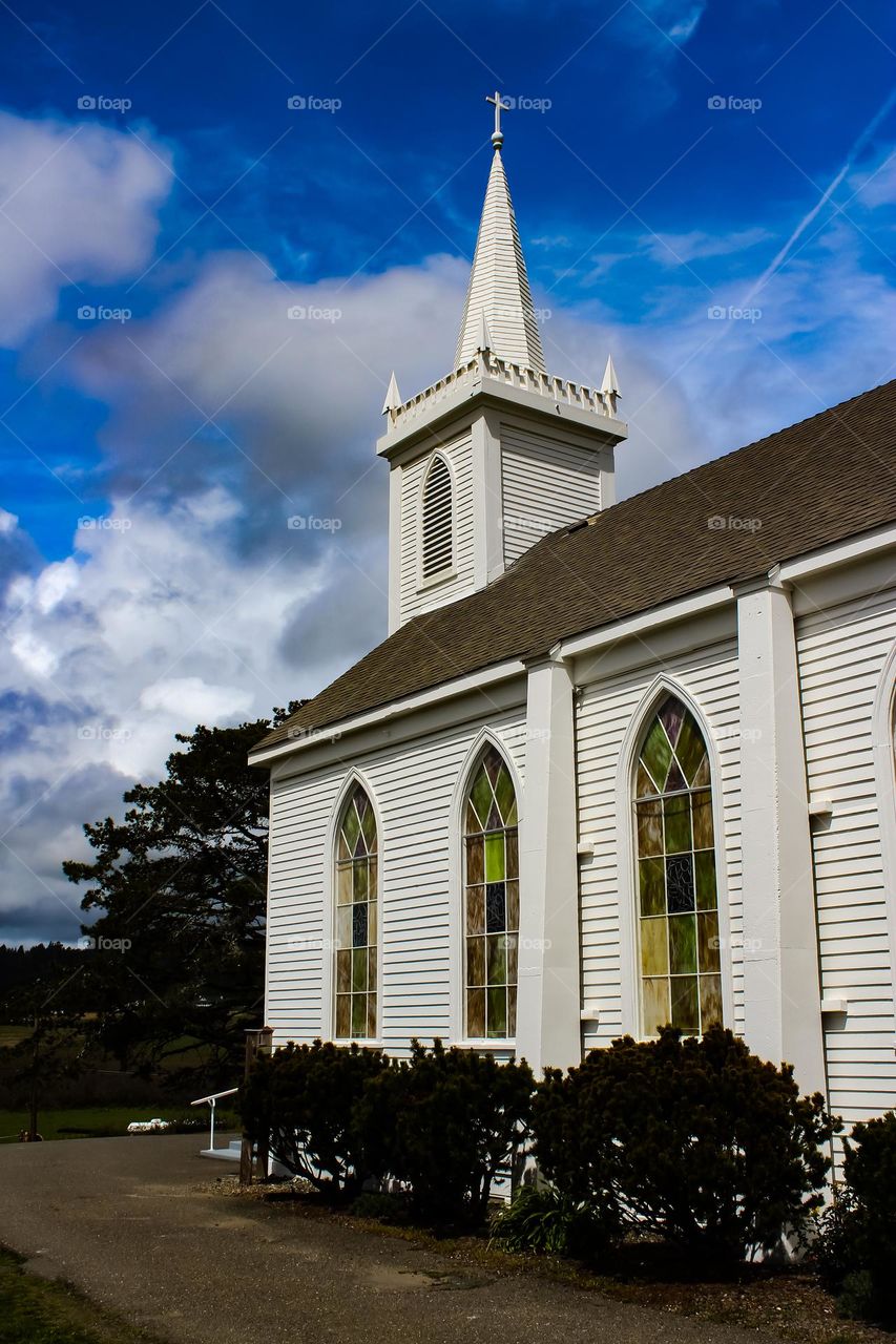 Stunning white church with a dramatic cloudy sky standing majestically with its stained glass windows and steeple