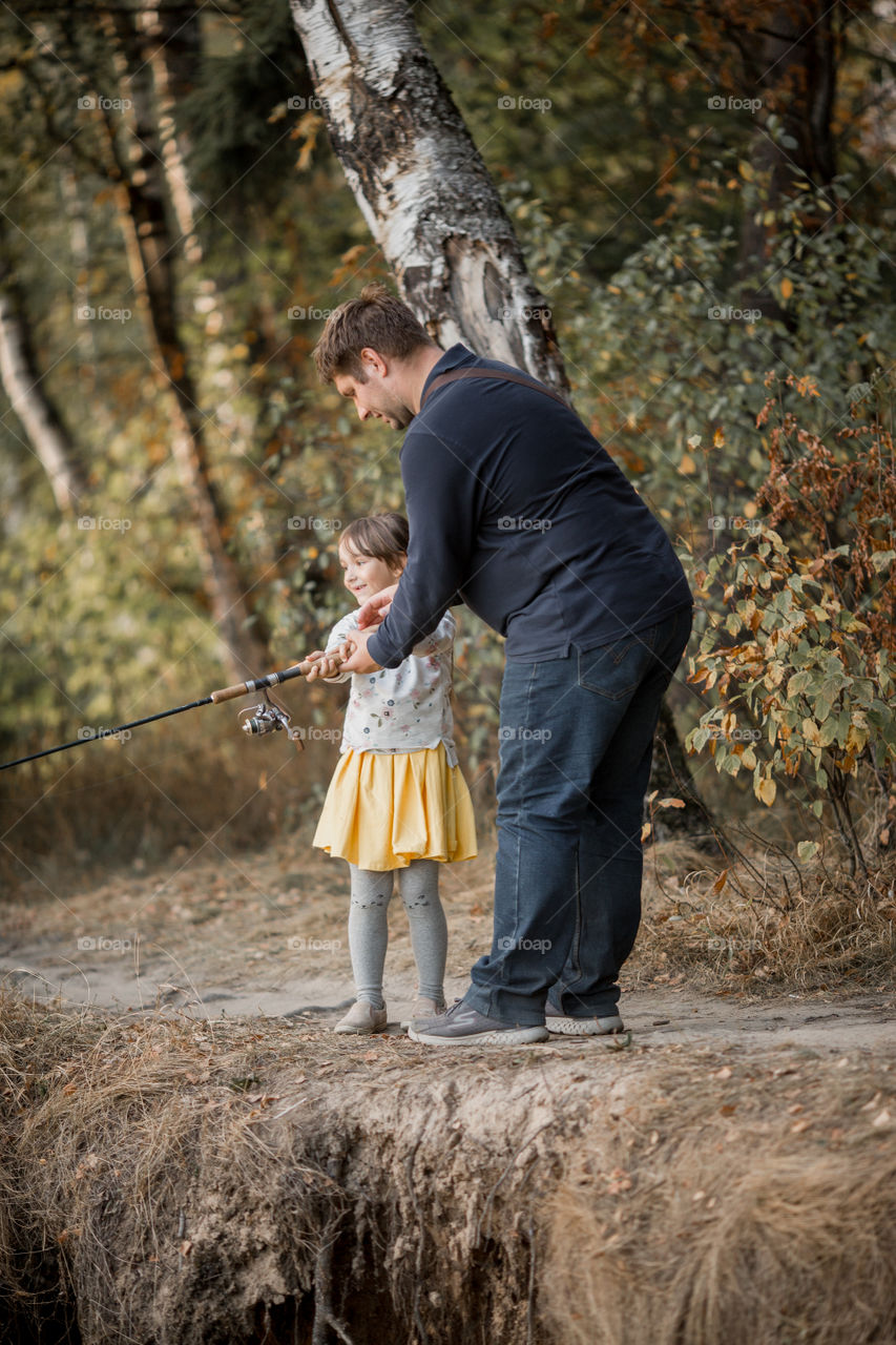 Family fishing on a lake at autumn day 