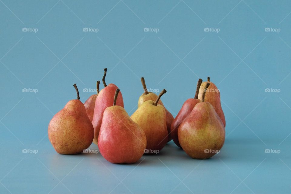 Still life with orange colored pears isolated on blue background. 