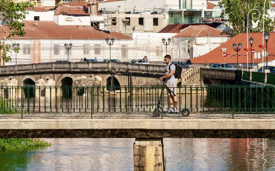 Man crossed a river bridge on a scooter