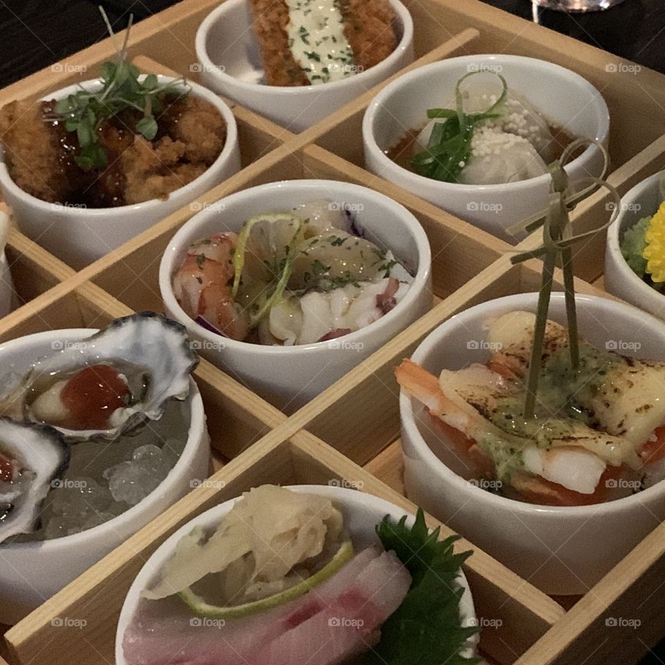 Samples of different Korean food in small bowls nicely arranged in squares of a tray