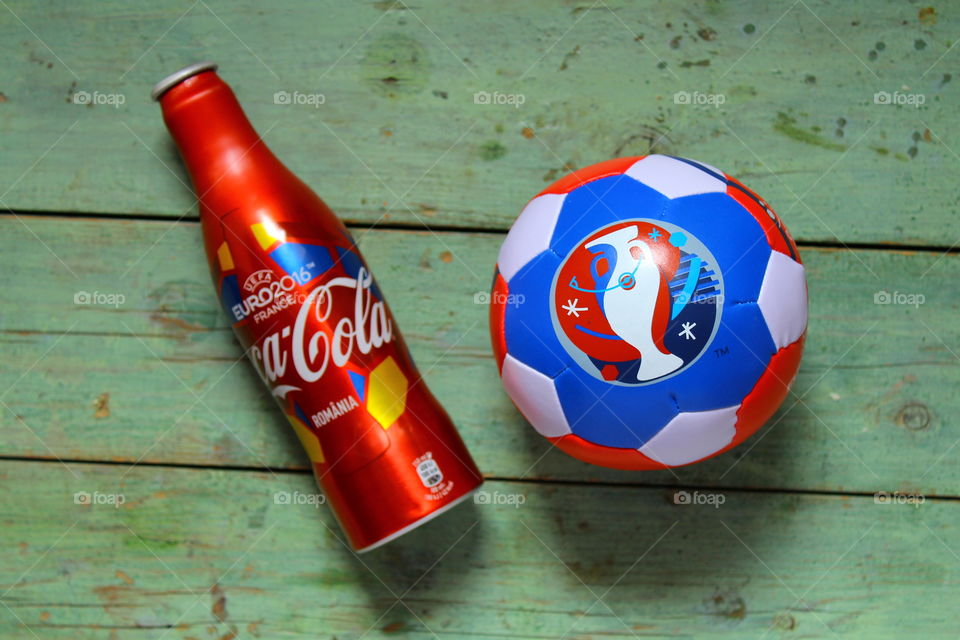 coca cola bottle and soccer ball on a wooden table