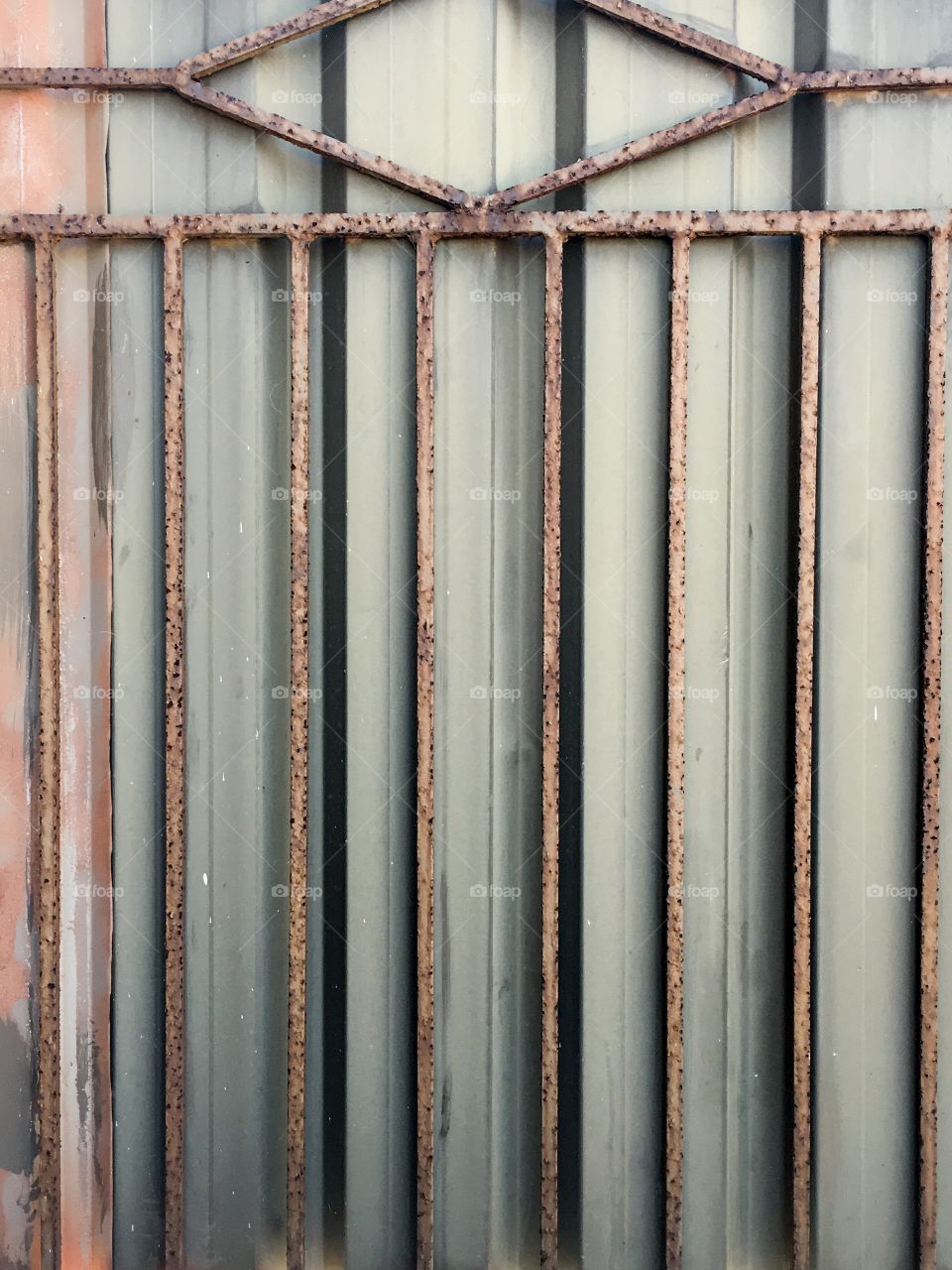 Grunge rusty iron fate against corrugated steels fence 