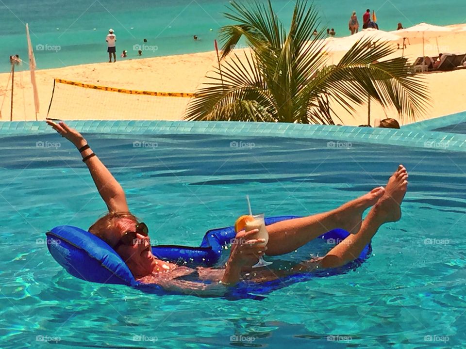 Me in the pool falling off of the float while enjoying my no he tell, tropical drink on the beach of Cancun Mexico palace resort sunshine vacation holiday with tropical paradise pool palm tree kicking back
