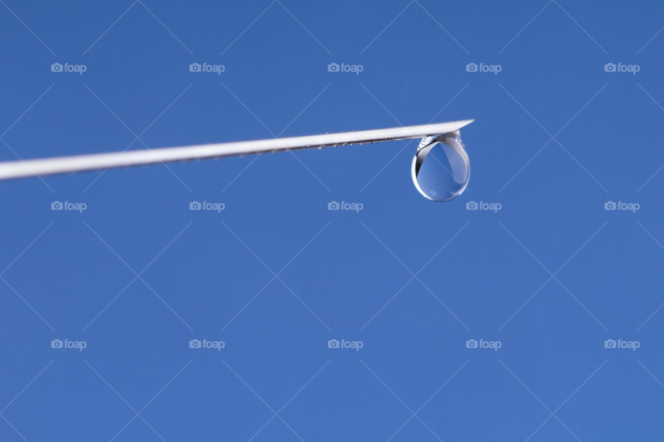 Close-up or macro of syringe needle with a drop at the tip on a blue background .Hospital, health, care, doctor, injection, vaccine, vaccination, illness, disease, sharpness concepts