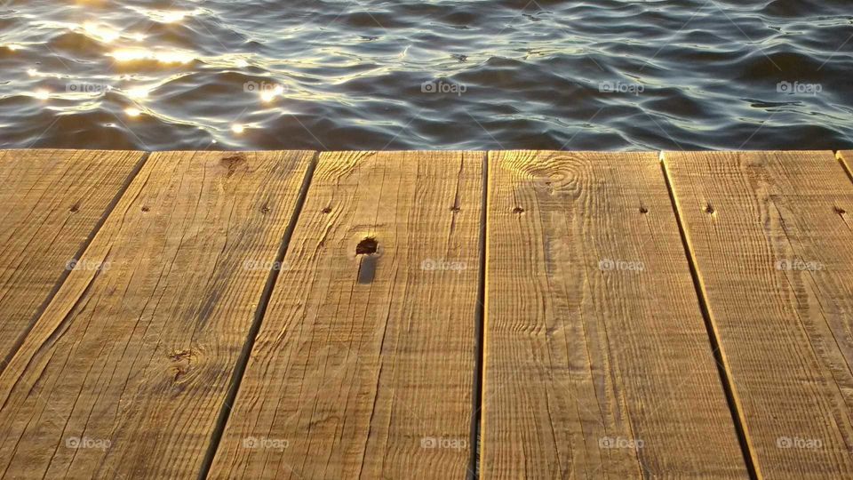 sunlight reflections on water and wooden dock