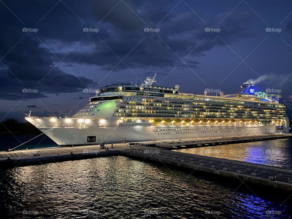 A cruise ship docked at a pier at night