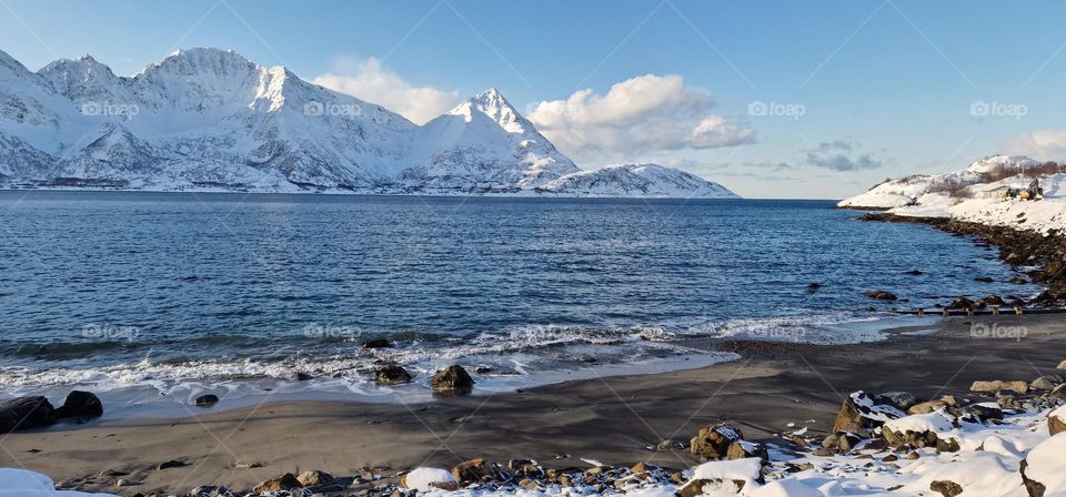 Icy and snow covered beach by the Arctic ocean in Northern Norway in March 2023.