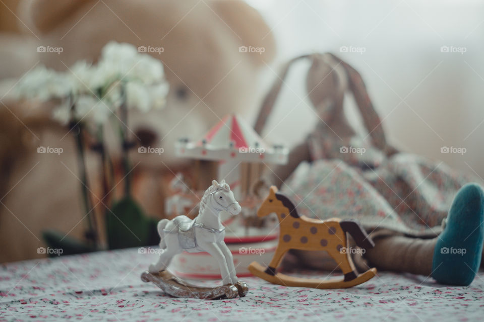 Children’s toys in room at daylight. Rocking horse, carousel, bunny, teddy bear