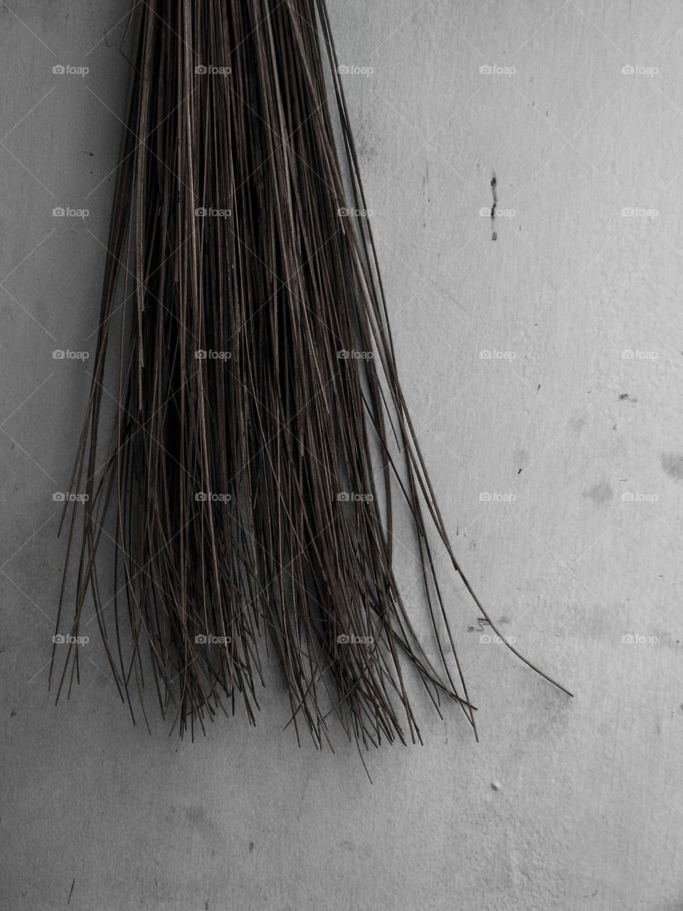 A natural fiber broom hanging on a white wall