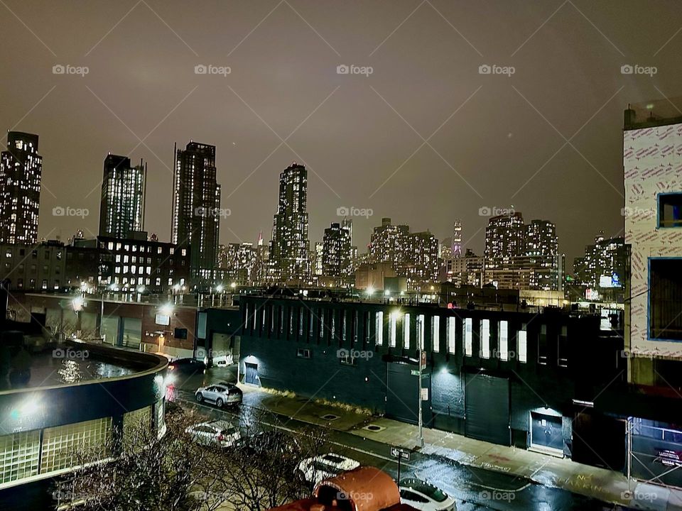This is an evening view from the staircase of the “Pulaski Bridge” at “Newtown Creek” on the “Greenpoint”, Brooklyn side of “Greenpoint” nearby and further away LIC and parts of “Manhattan”. 2023. Hypnotic Productions