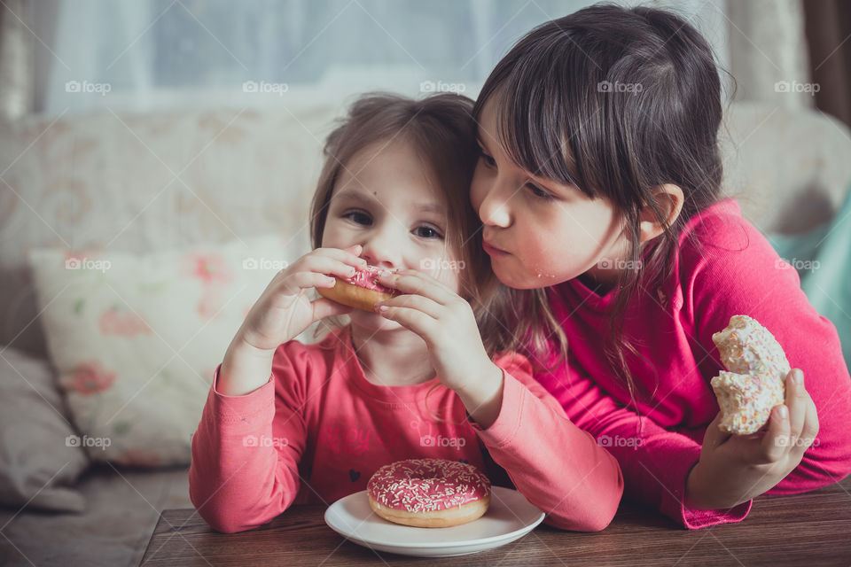 Little sisters eating donuts 