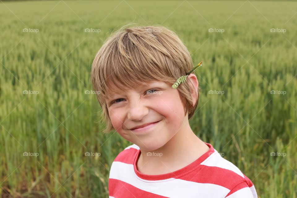 Child in a field with wheat behind his ear 