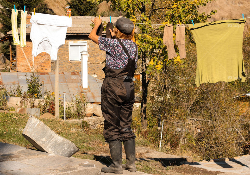 A woman hangs the laundry to dry on the rope at the backyard