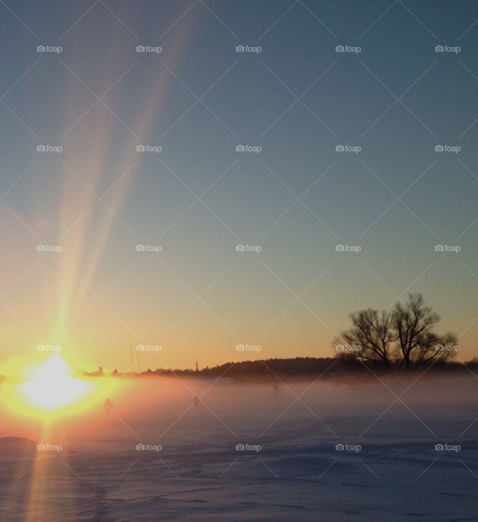 Sunrays over foggy, snowy landscape 