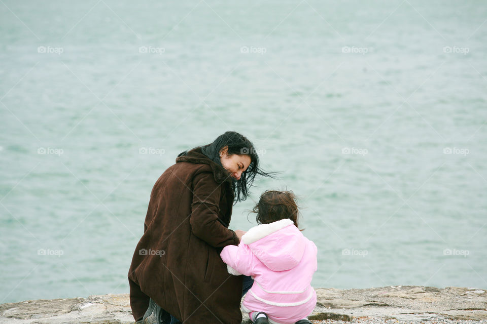 back view of mother and daughter in spring sea