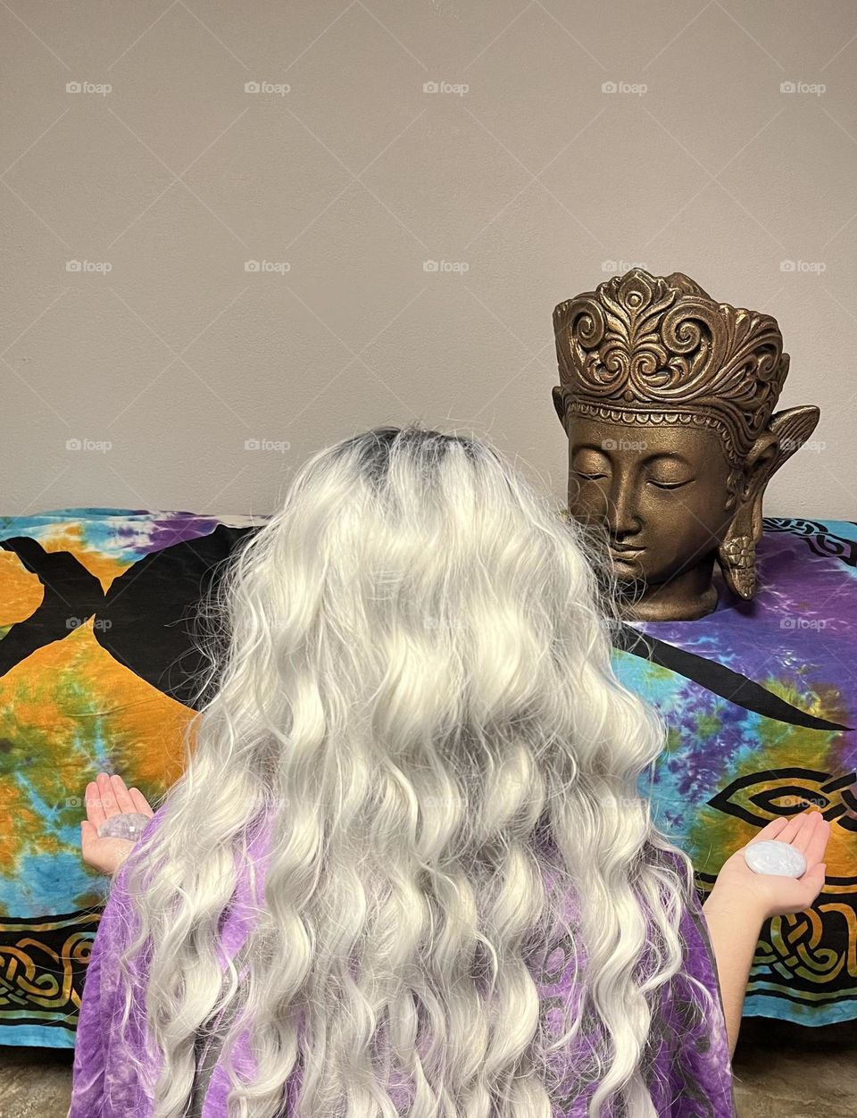 A woman meditating in front of a golden Buddha.