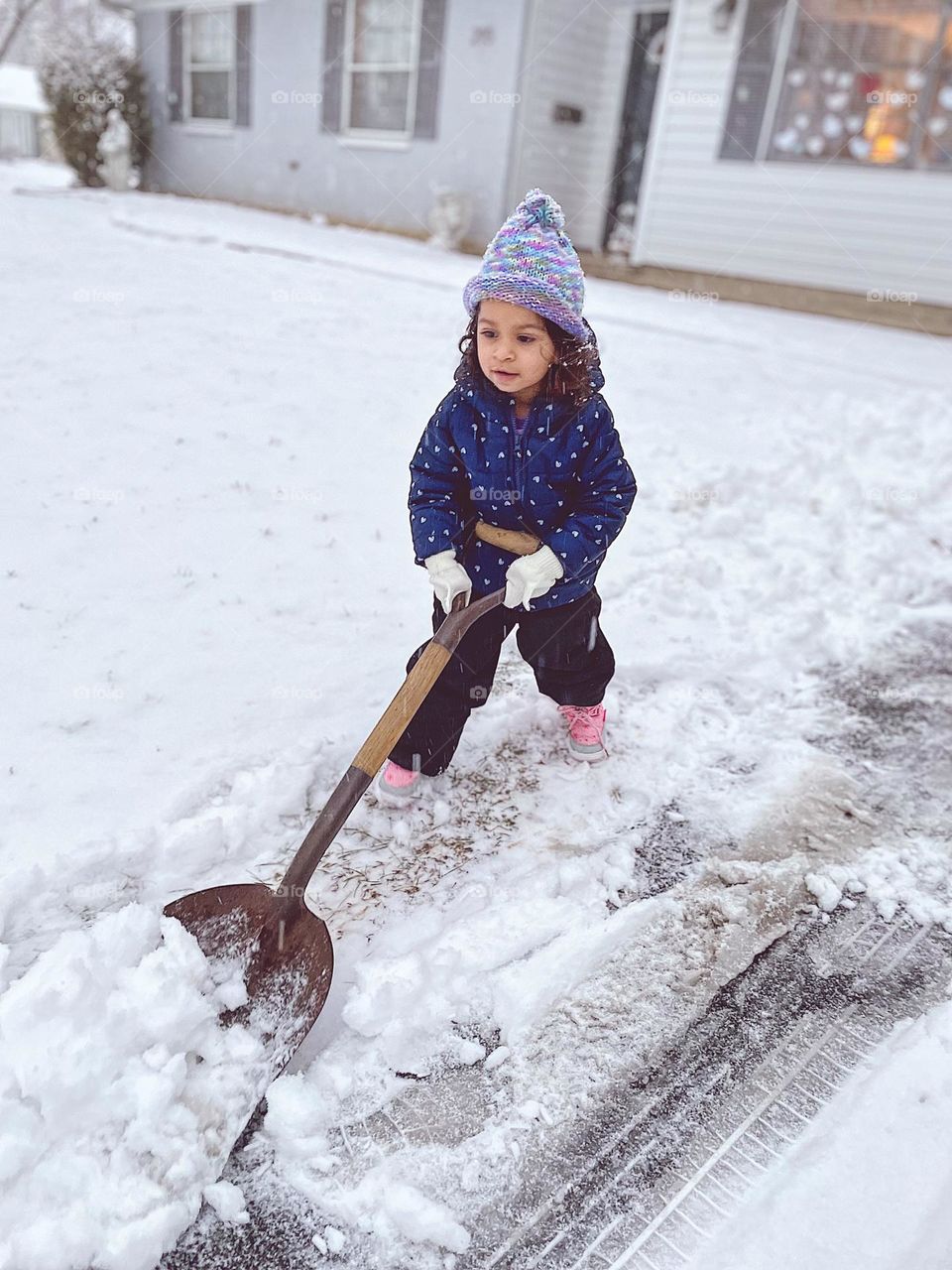 Toddler shovels snow in the Midwest, Midwestern winters with lots of snow, child playing in the snow, child  helps mommy shovel snow, toddler helps clear snow from driveway, wintertime snow showers