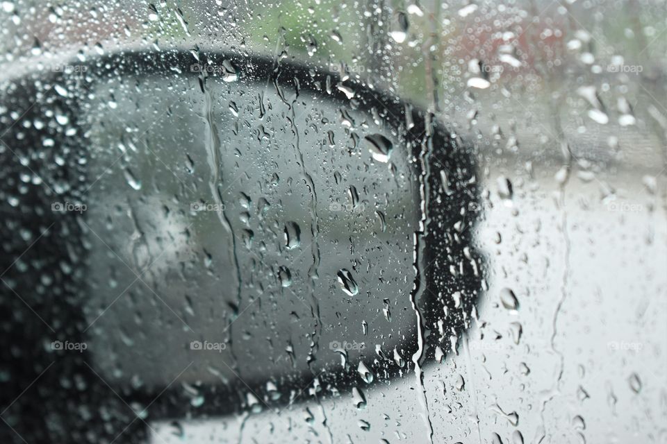 falling rain drops over car mirror