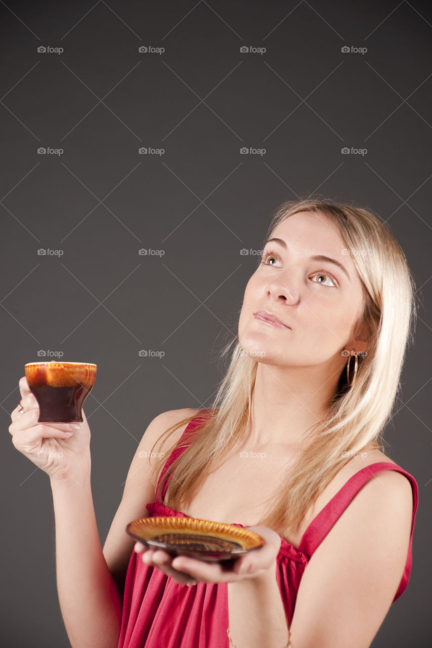 Girl with a coffee cup dreams. Isolated over gray.