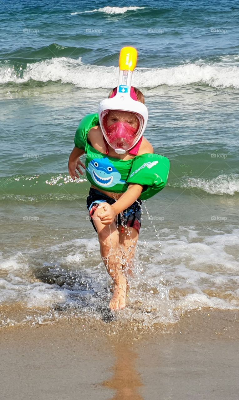 a boy with snorkel coming up from water