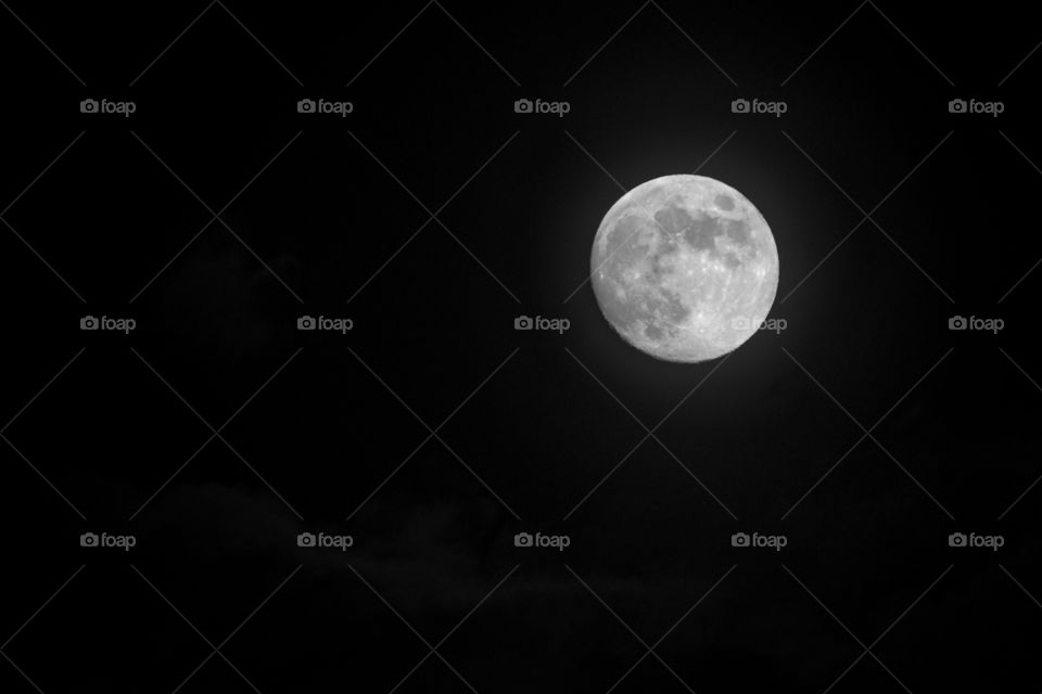The moon is the subject with a dark background and subtle clouds. The moon is placed using the rule of thirds and the background was darkened to keep the focus on the subject. 