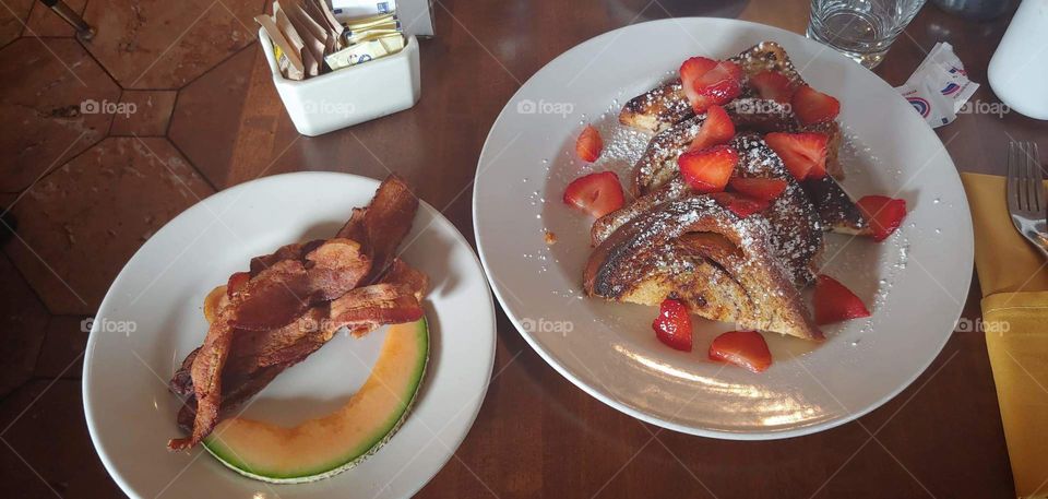 Delicious Morning Breakfast. Mouth Watering Strawberries and Cantaloupe with Perfectly Crisped Bacon and French Toast  Raisin Bread.