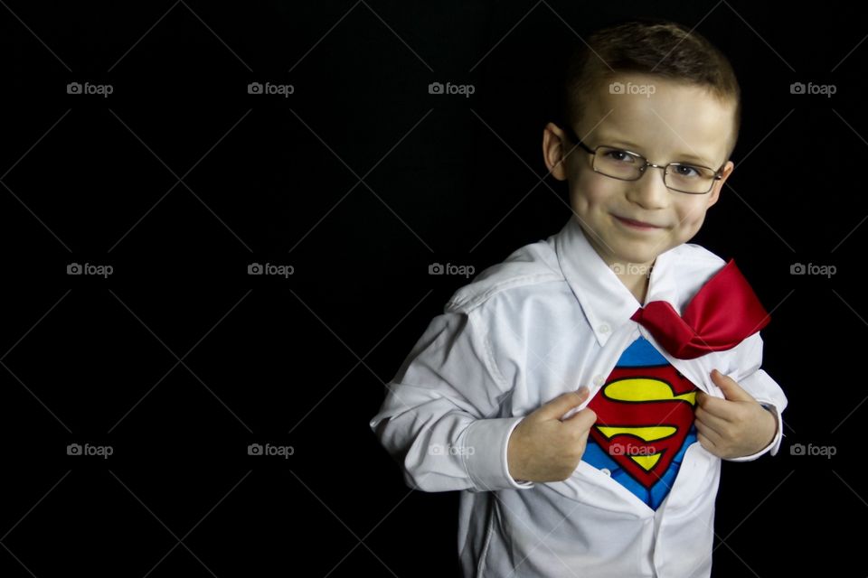 Superhero unbuttoning his shirt on black background