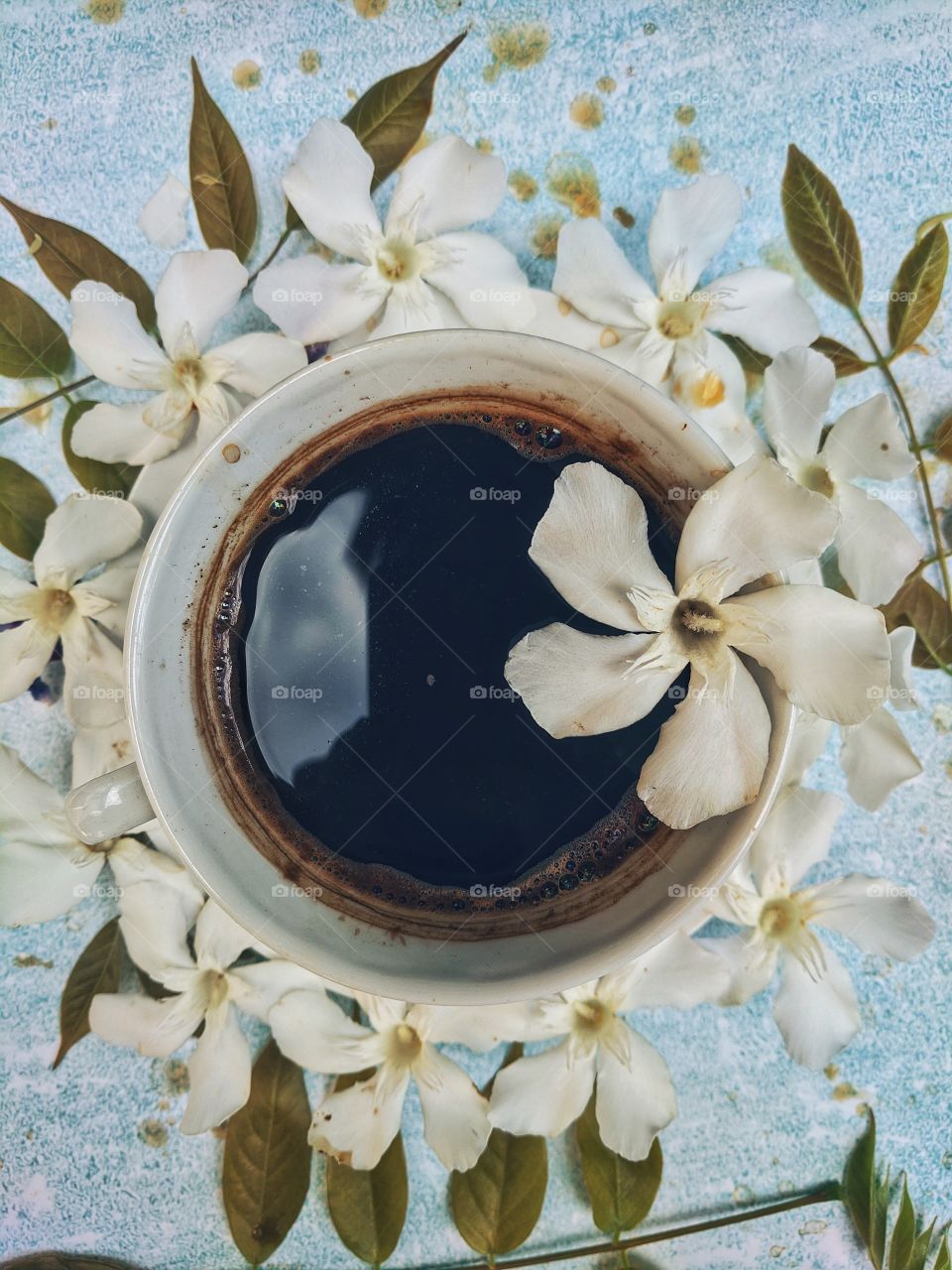 Background of a cup of hot coffee on the table with beautiful flowers close-up. Top view.