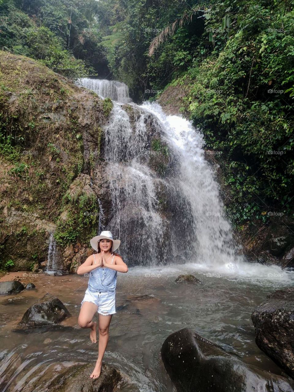 Portrait of woman standing against waterfall