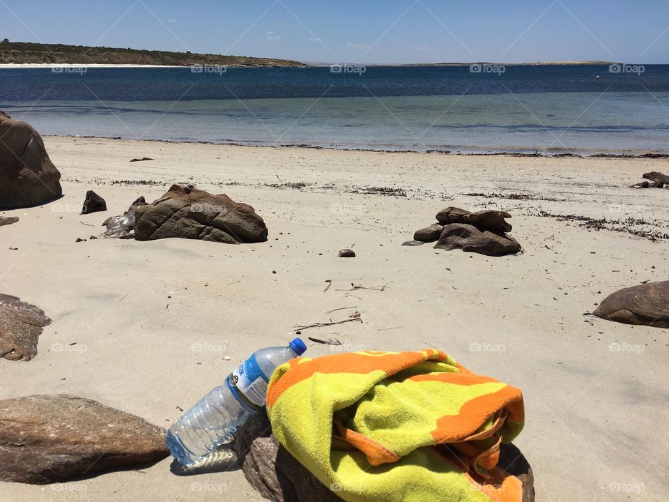 Colourful towel on remote south Australian beach, ocean horizon in distance, rocks on beach