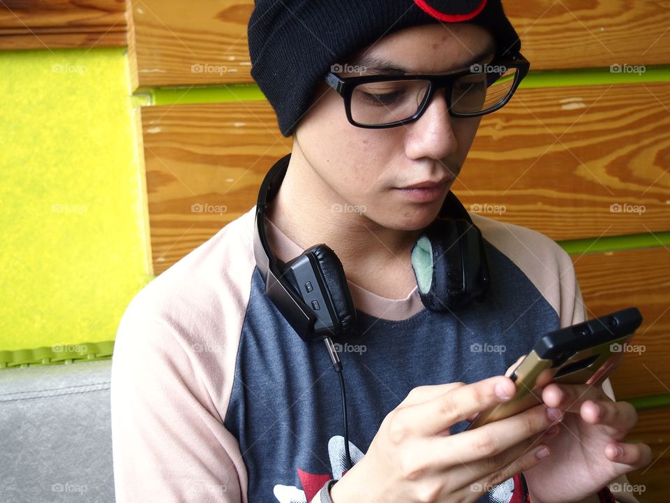 teenage boy wearing bonnet using a smartphone