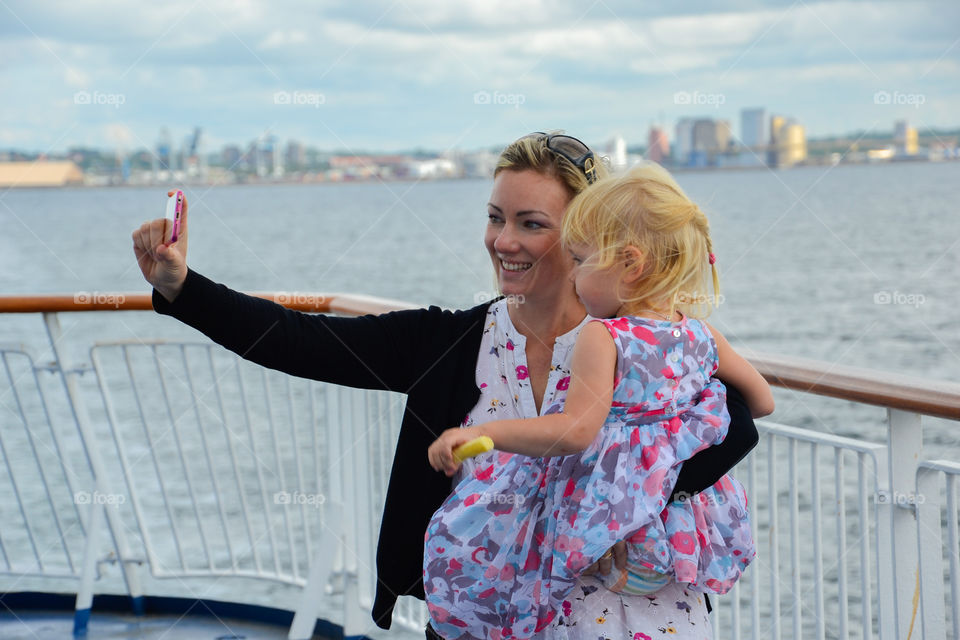 Beautiful mother and little daughter taking selfie with smartphone
