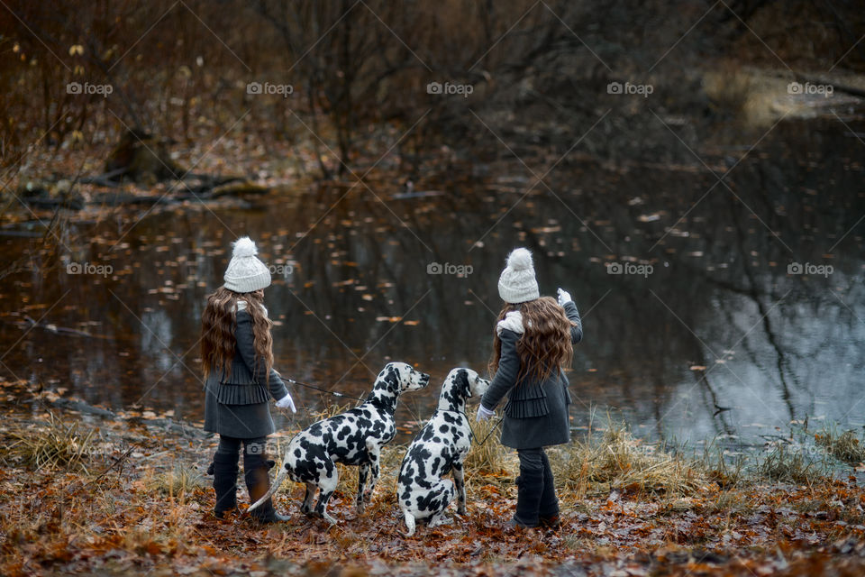 Twins girls with Dalmatian dogs in autumn park 