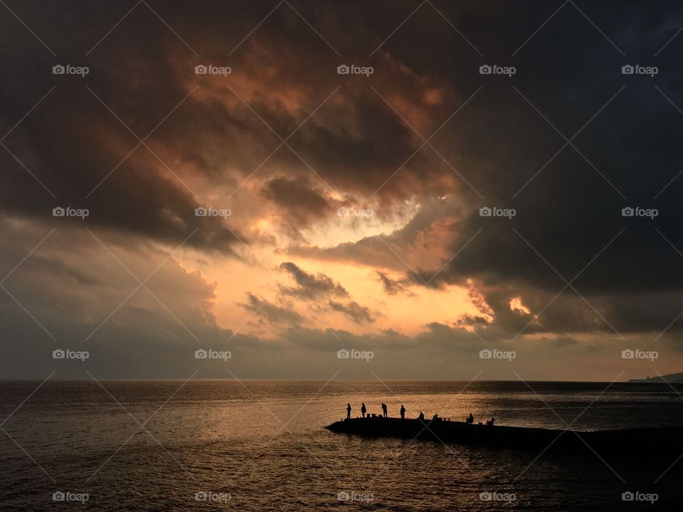 Sunset above the sea and fishermen. 