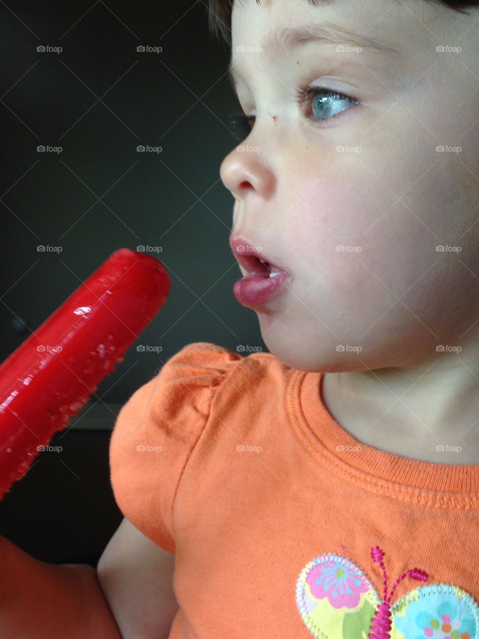 Girl eating red Popsicle 