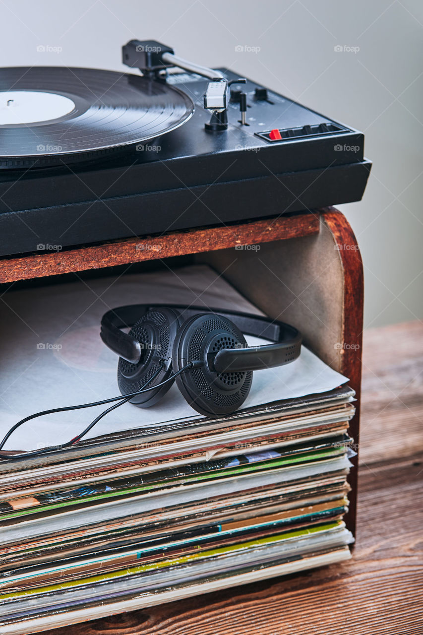 Stack of black vinyl records, turntable vinyl player and headphones. Classic stereo set. Candid people, real moments, authentic situations