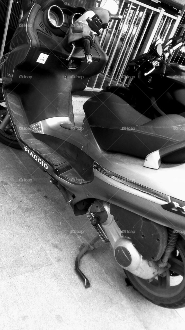 Black Piaggio brand motorcycle parking
in street on pavement in daylight