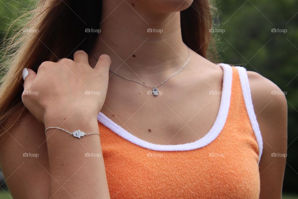 Female teenager in orange tank shirt wearing bracelet and necklace 