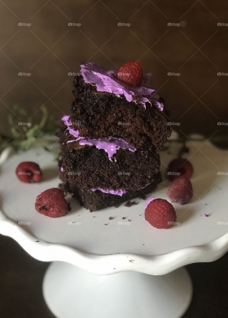 A yummy delicious chocolate cake with purple frosting and red raspberries on top makes me happy! 