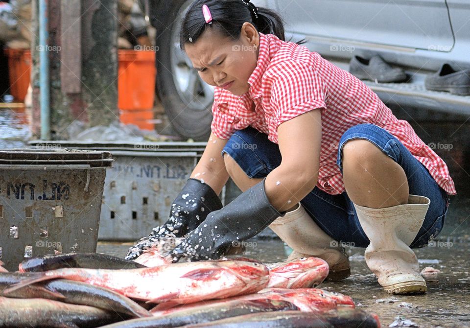 A woman is cleaning fish at a wholesale market in Bangkok, Thailand.