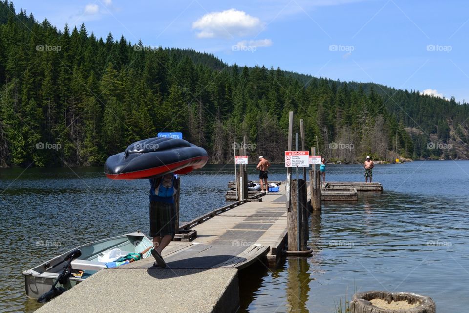 Kayak down the dock. Inflatable kayak carried down dock at lake