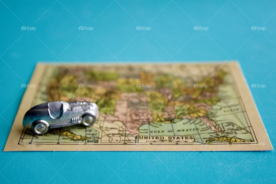 Miniature silver racer heading northwest on a miniature vintage map of the United States of America against a sky blue background