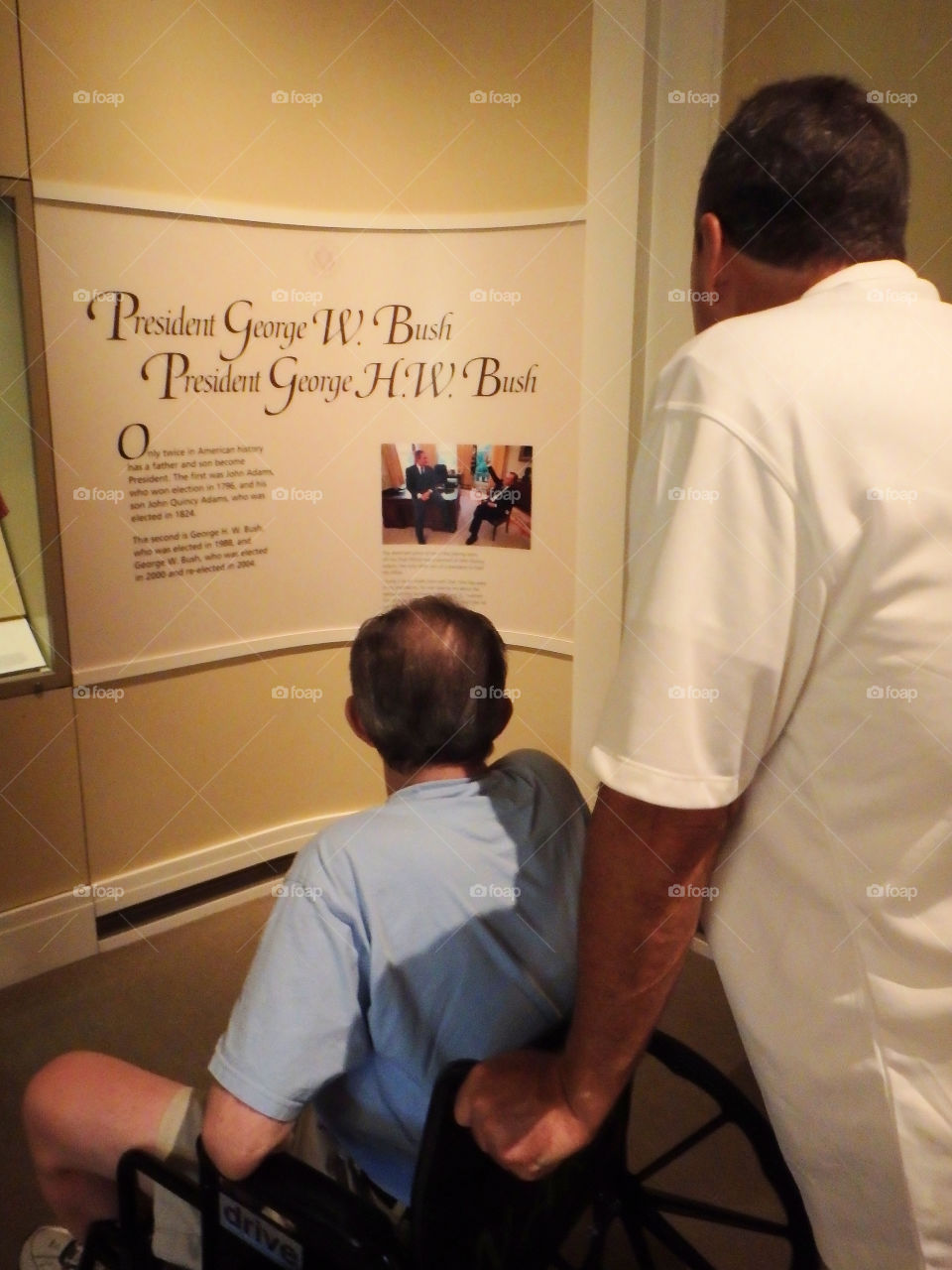 A doting son pushes his elderly father in the Bush Presidential Library in Dallas, TX.
